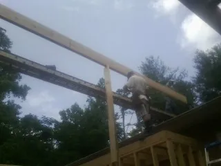 Carpenter setting a ridge beam over a new addition frame — Ice Dam Removal by Roofing Brothers in Bostwick