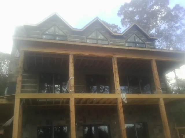 Dormers and porch framing on a large log home under construction — Roof Coating work by our crew in Bostwick