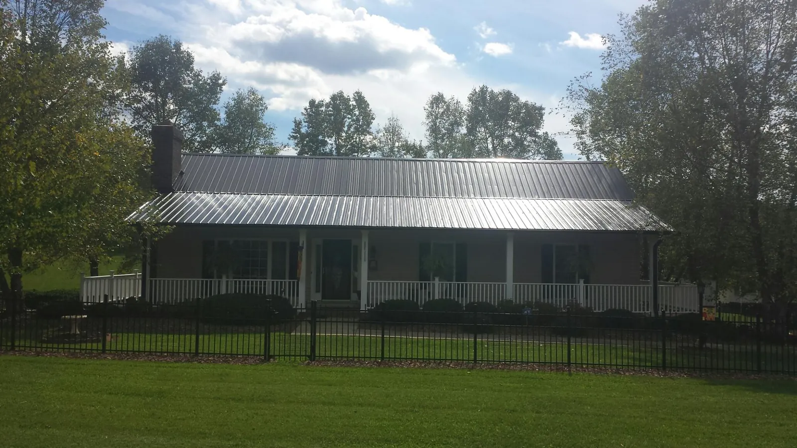 Gray metal roof on a brick ranch with a full width front porch — Gutter Guard Installation work by our crew in Bostwick